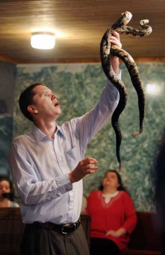 Andrew Hamblin, 21, pastor of Tabernacle Church of God in La Follette, Tenn., holds up two rattlesnakes during church service. For more than a 100 years, small Pentecostal churches in East Tennessee and other parts of Appalachia have handled poisonous snakes and drunk strychnine during their services. The snake handlers say that the Bible tells them to do so, but it?s illegal and has mostly died out. RNS photo by Shelley Mays/courtesy USA Today  