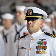 Lt. Cmdr. Jose Arana, maintenance officer for Helicopter Sea Combat Squadron (HSC) 9, stands at attention during a change of command ceremony in the squadron’s hangar at a Naval station. Photo courtesy of Official Navy Page from United States of America MC2 Timothy Walter/U.S. Navy [Public domain], via Wikimedia Commons