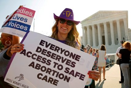 A demonstrator wearing a cowboy hat with a uterus symbol holds a sign outside the U.S. Supreme Court as the court is set to rule on a legal challenge by abortion providers to a Texas law requiring doctors performing the procedure to have "admitting privileges" at local hospitals and clinics to meet hospital-grade standards in Washington, U.S. June 27, 2016. REUTERS/Kevin Lamarque